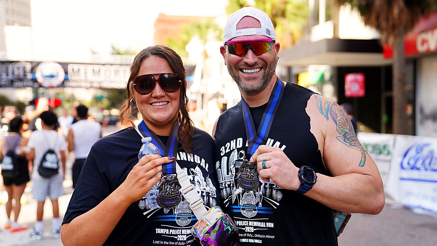 Two runners smiling with their finisher medals and 32nd Annual Memorial Run shirts